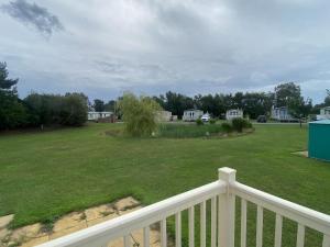 a large yard with a white fence and a large lawn at Oak Village 64 - Grange Leisure disability caravan - pet friendly, wifi and ramped decking in Mablethorpe