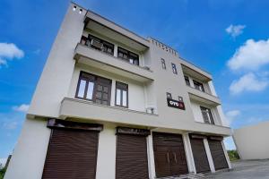 ein weißes Gebäude mit braunen Fensterläden darauf in der Unterkunft SPOT ON Samrat Hotel in Kānpur