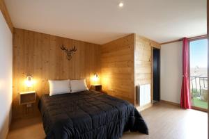una camera da letto con un letto con pareti in legno e una finestra di Le Hibou - Grand Appartement, Vue Montagne a Les Angles