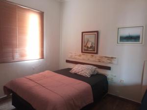 een slaapkamer met een bed en een raam bij Cobertura com churrasqueira São Vicente in São Vicente