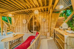 a room with a red couch in a bamboo house at Balikayanas - Yumi House in Mantaak +24 photos