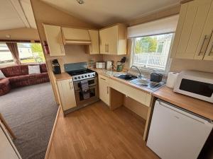 a small kitchen with a stove and a microwave at Disabled caravan -ramped decking - Grange Leisure Park, Mablethorpe - Pet friendly and Wifi - Meadow Lakes Caravan & Lodge Hire in Mablethorpe