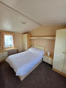 a bedroom with a large white bed and a window at Disabled caravan -ramped decking - Grange Leisure Park, Mablethorpe - Pet friendly and Wifi - Meadow Lakes Caravan & Lodge Hire in Mablethorpe