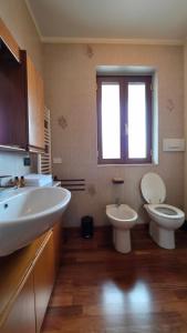Un baño con dos lavabos y un inodoro y una ventana. en Dimora Einaudi, en Cravanzana