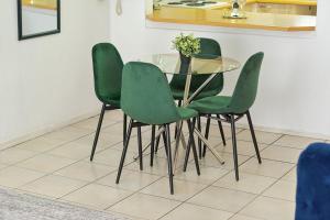 a glass table and four green chairs in a room at Chic 2BR Apartment in Roodepoort in Roodepoort
