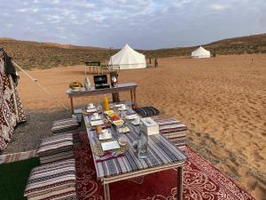 a table in the middle of a desert with tents at ShootingStar Private Camp in Shāhiq