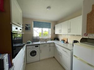 a kitchen with a sink and a washing machine at Sunny detached bungalow, Nr Looe in Saint Keyne