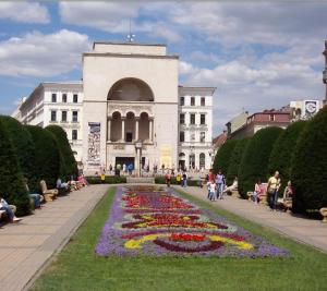 ein Gebäude mit einem davorliegenden Blumengarten in der Unterkunft Central, big terrace, near river in Timişoara