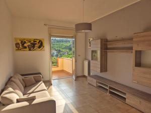 Una sala de estar con un sofá y una ventana grande. en Casa Egle - Between Etna and the sea, en Giarre