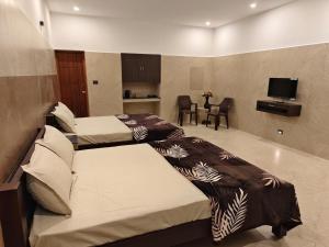 Una habitación de hotel con dos camas y un televisor. en RR Holiday Grand, en Kodaikanal