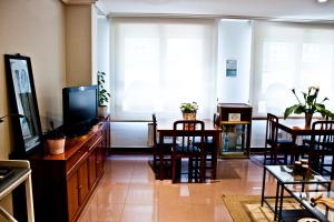 - un salon avec une télévision, une table et des chaises dans l'établissement Hotel Playa Poniente, à Gijón