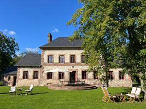 a large stone house with chairs and a table at Manoir de Daubeuf in Daubeuf-Serville
