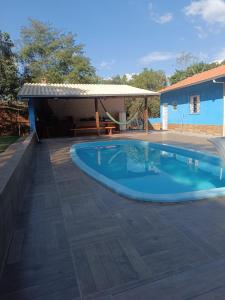 a swimming pool with a patio and a house at Recanto Paraíso in Rio Piracicaba