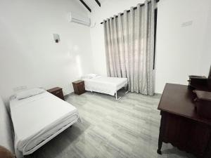 a bedroom with two beds and a desk and a piano at Villa J&T in Katunayake