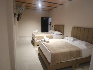 a room with two beds and a fan at Hotel Country Medellin in Medellín