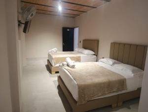 a room with two beds and a fan at Hotel Country Medellin in Medellín