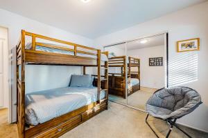 a bedroom with bunk beds and a chair and a mirror at Moose-in' Around ~ Walk to Slopes Mountain Home with Private Hot Tub, Ski Locker & Playground in Big Bear Lake