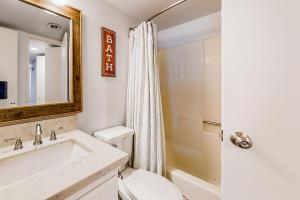 a bathroom with a sink and a toilet and a mirror at Moose-in' Around ~ Walk to Slopes Mountain Home with Private Hot Tub, Ski Locker & Playground in Big Bear Lake
