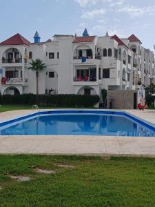 a large apartment complex with a swimming pool in front of a building at Coastal Elegance in Oulad Akkou