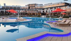 a swimming pool with chairs and umbrellas in front of a building at Baytur-Yilla09 in Bosteri