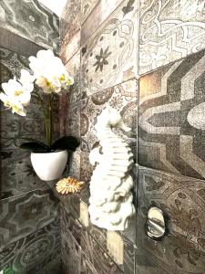 een muur met een kattenbeeld en een vaas met bloemen bij il gioiello del mare in Lido di Ostia +3 foto's