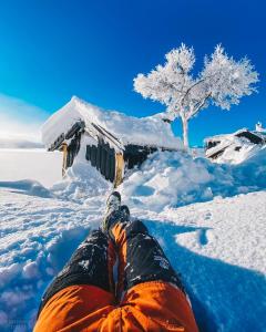 une personne assise dans la neige avec ses jambes en haut dans l'établissement Soleiknuten Ålsheia Moderne Hytte i Naturskjønne Omgivelser, à Tjørhom