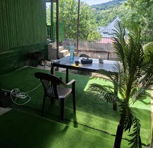 a patio with a table and a chair and a palm tree at CABANUȚA de sub Masivul Penteleu in Varlămul