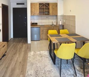 a kitchen with a wooden table and yellow chairs at Kalamata apartman, K Kompleks Jagodina in Trnava