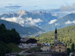 a town with a clock tower and mountains in the background at Il Giardino sull'Antelao in Masariè