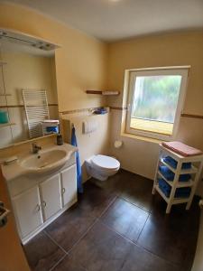 Un baño con lavabo, inodoro y ventana. en Bungalow in Kühlungsborn, en Kühlungsborn