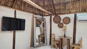 a tv on a wall with a table and a mirror at Casa Pakluum in Felipe Carrillo Puerto