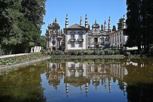 an old mansion with a reflection in a pond at Casa do Adro de Parada in Parada de Pinhão