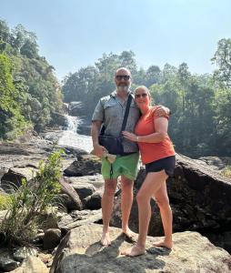 a man and woman standing on rocks near a waterfall at 4Seasons Holiday Home in Ratnapura