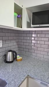 a kitchen counter with a tea pot and a microwave at Arequito centro in Arequito +5 photos