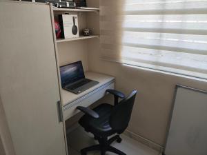 a laptop computer sitting on a desk with a chair at Cobertura Pampulha in Belo Horizonte