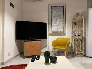 a living room with a tv and a yellow chair at La Casa al Mare in Scalo dei Saraceni Manfredonia
