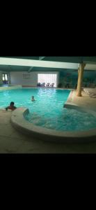 a swimming pool with two people in the water at Mobil-home 3 chambres 6 personnes in Saint-Hilaire-de-Riez +3 photos