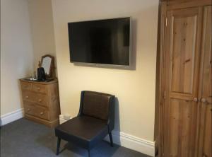 a room with a chair and a television on the wall at 106 Brynmill - Room 4 in Sketty