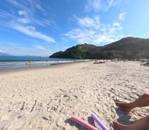 a sandy beach with a group of people on it at Casa aconchegante à 2 minutos da praia em Prainha de Mambucaba Paraty in Paraty
