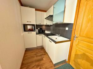 a small kitchen with white cabinets and a sink at Appartement 6 personnes - Les Menuires, vue montagne - FR-1-452-111 in Les Menuires