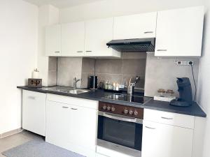 a kitchen with white cabinets and a stove top oven at Ferienwohnung LAZ am Dreiländereck in Bad Säckingen