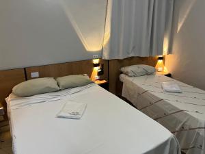 two beds in a small room with two lamps at Hotel Tropicália próximo a 25 de março , Brás e Bom Retiro "Com estacionamento conveniado ao lado do hotel" in São Paulo
