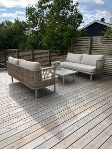 two couches and a table on a wooden deck at Modern 3 bedroom villa 10min from Oslo Airport Gardermoen in Jessheim