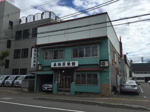 a green building with writing on the side of it at Mimatsuso Ryokan in Asahikawa