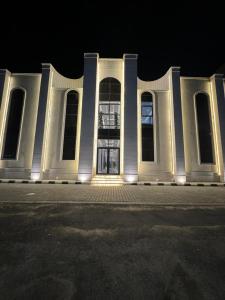 a large white building with windows at night at شقق المها وصول ذاتي in Hafr Al Baten +9 photos