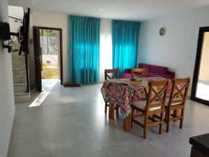 a dining room with a table and chairs and blue curtains at Edén 15 in La Falda