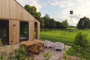 een patio met een houten tafel en witte stoelen bij Gastenverblijf Beekweide - de Notenboom in Voorst