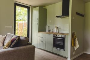 een woonkamer met een bank en een keuken bij Gastenverblijf Beekweide - de Notenboom in Voorst +9 foto's