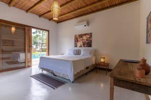 a white bedroom with a bed and a table at Casa Marlim - Trancoso Eco Residence in Porto Seguro