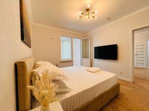 a bedroom with a bed and a tv on the wall at Good mood in Astana